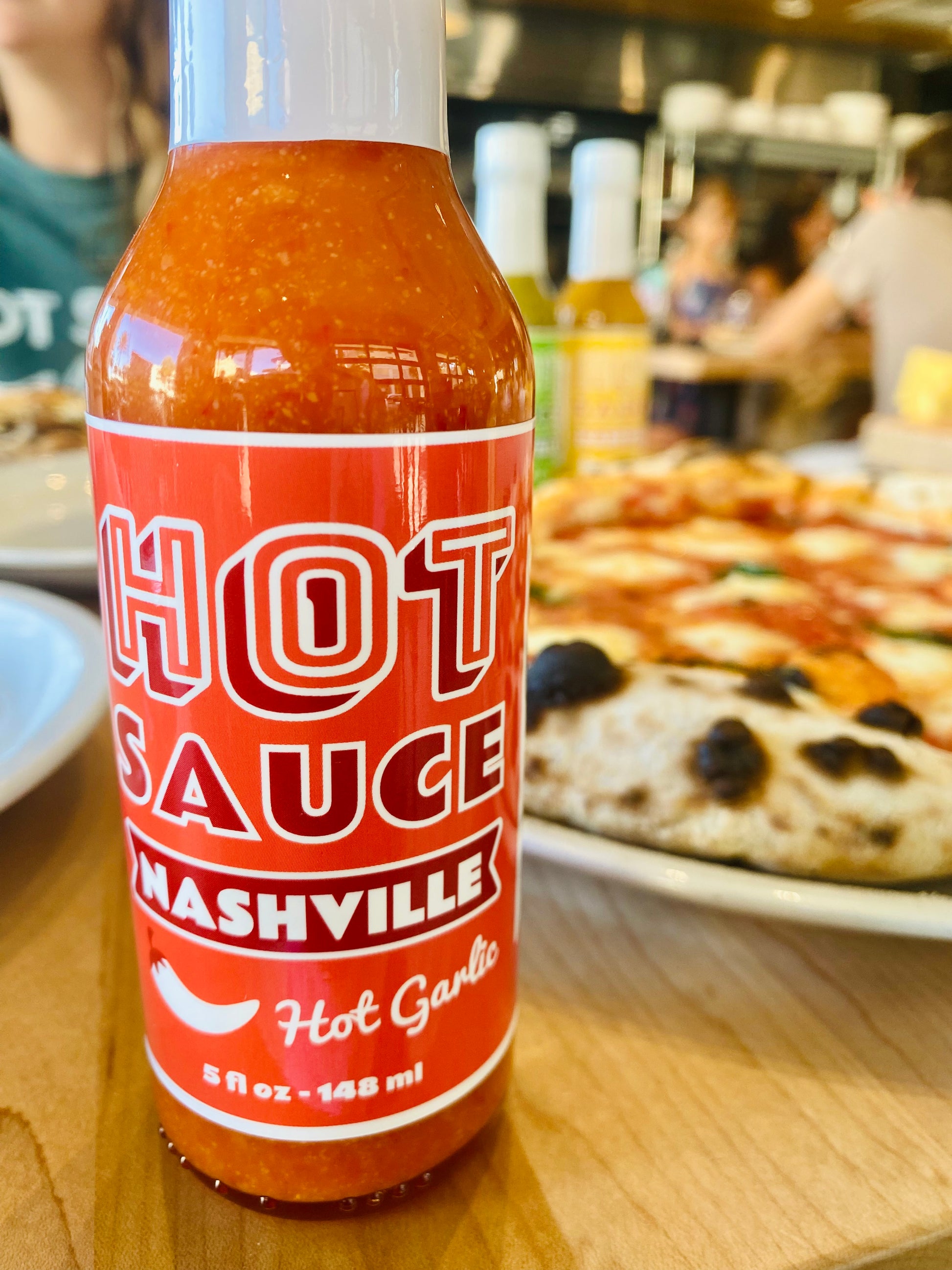 Bottle of Hot Garlic in Front of Pizza