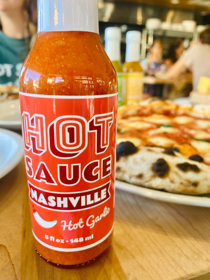 Bottle of Hot Garlic in Front of Pizza